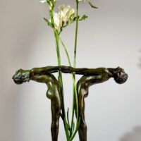 Alt text: Bronze sculpture of two figures holding hands, with flowers between them