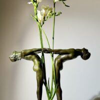 Alt text: Bronze sculpture of two figures holding hands, with flowers between them