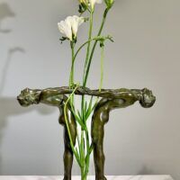 Alt text: Bronze sculpture of two figures holding hands, with flowers