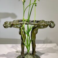 Alt text: Bronze sculpture of two figures holding hands, with flowers