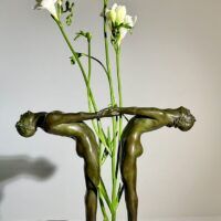 Alt text: Bronze sculpture of two figures holding hands, with flowers