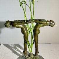 Alt text: Bronze sculpture of two figures holding hands, with flowers