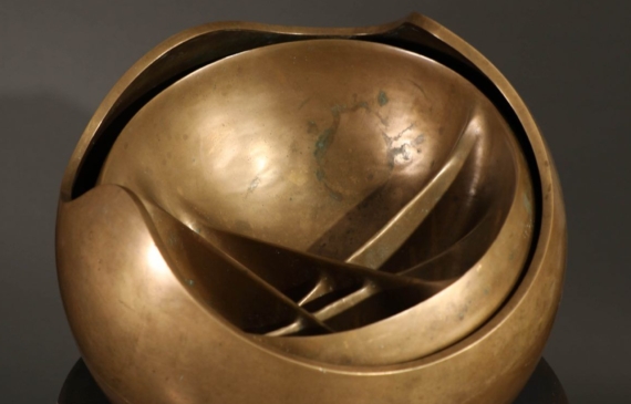 Alt text: Abstract bronze sphere atop a bronze column, top view
