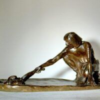 Alt text: Bronze sculpture of a crouching man with outstretched arm