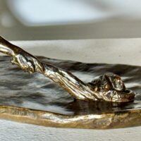 Alt text: Bronze sculpture of a crouching man with outstretched arm, detail