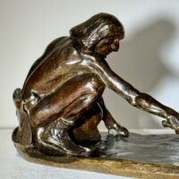 Alt text: Bronze sculpture of a crouching man with outstretched arm