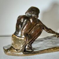 Alt text: Bronze sculpture of a crouching man with outstretched arm