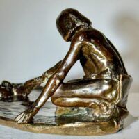 Alt text: Bronze sculpture of a crouching man with outstretched arm
