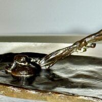 Alt text: Bronze sculpture of a crouching man with outstretched arm, detail