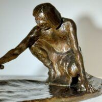 Alt text: Bronze sculpture of a crouching man with outstretched arm