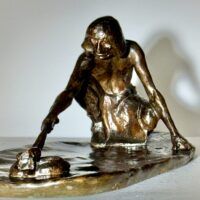 Alt text: Bronze sculpture of a crouching man with outstretched arm