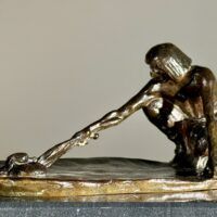 Alt text: Bronze sculpture of a crouching man with outstretched arm