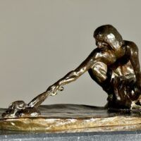 Alt text: Bronze sculpture of a crouching man with outstretched arm