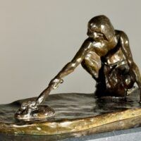 Alt text: Bronze sculpture of a crouching man with outstretched arm