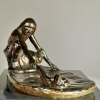 Alt text: Bronze sculpture of a crouching man with outstretched arm