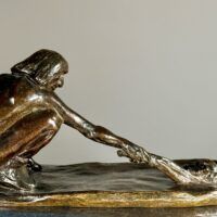 Alt text: Bronze sculpture of a crouching man with outstretched arm