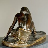 Alt text: Bronze sculpture of a crouching man with outstretched arm