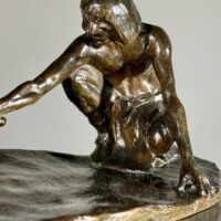 Alt text: Bronze sculpture of a crouching man with outstretched arm