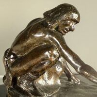 Alt text: Bronze sculpture of a crouching man with outstretched arm