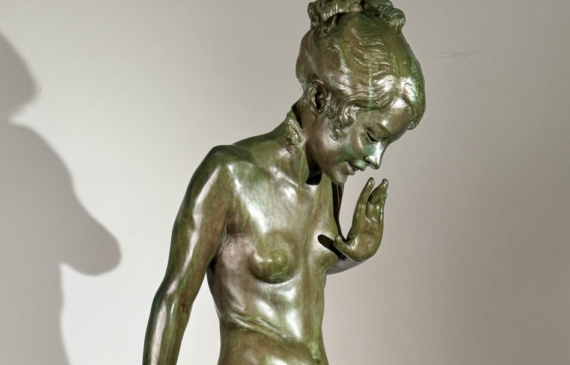 Alt text: Bronze sculpture of a young nude woman standing among frogs