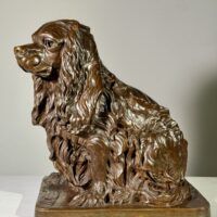 Alt text: Bronze sculpture of a seated dog, side view