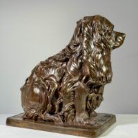Alt text: Bronze sculpture of a seated dog, side view
