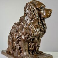 Alt text: Bronze sculpture of a seated dog, side view