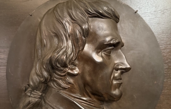 Alt text: Bronze relief portrait of a man's side profile