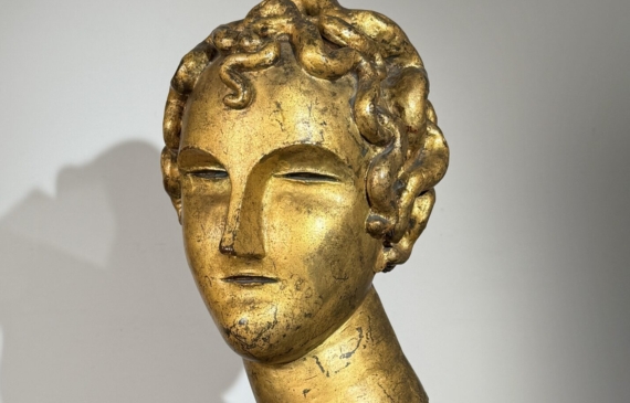 Alt text: Gilt bronze sculpture of a head of a boy with curly hair