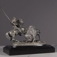 Alt text: Metal sculpture of a Native American man on horseback spearing a buffalo