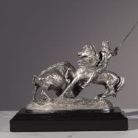 Alt text: Metal sculpture of a Native American man on horseback spearing a buffalo