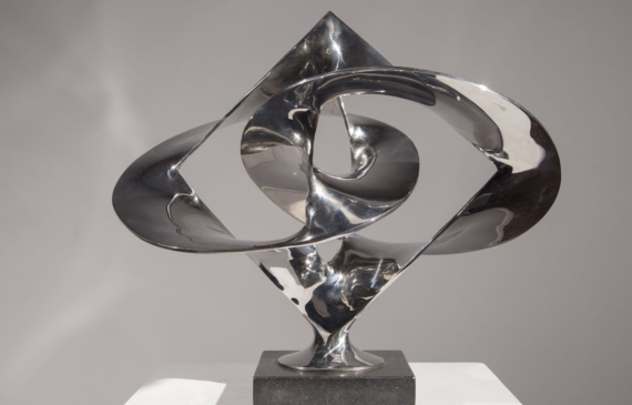Alt text: Polished bronze sculpture of large distorted circles interlocked