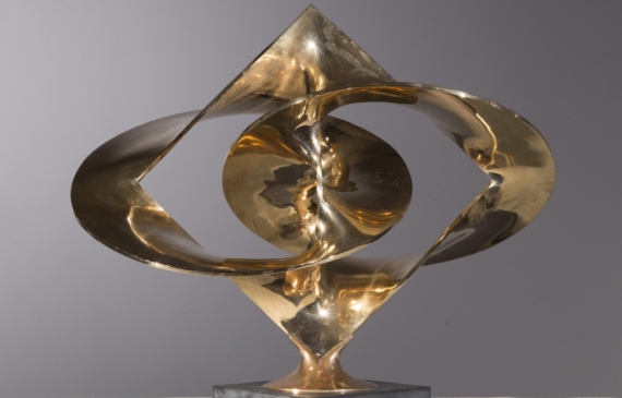 Alt text: Polished bronze sculpture of large distorted circles interlocked