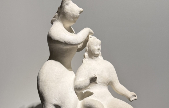 Alt text: White sculpture of two women, one standing and one seated