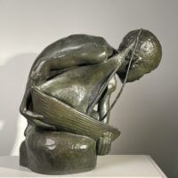 Alt text: Bronze sculpture of a crouching boy holding a sailboat