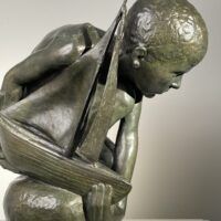 Alt text: Bronze sculpture of a crouching boy holding a sailboat