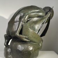 Alt text: Bronze sculpture of a crouching boy holding a sailboat