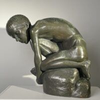 Alt text: Bronze sculpture of a crouching boy holding a sailboat