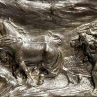 Alt text: Bronze relief of men with horses, detail